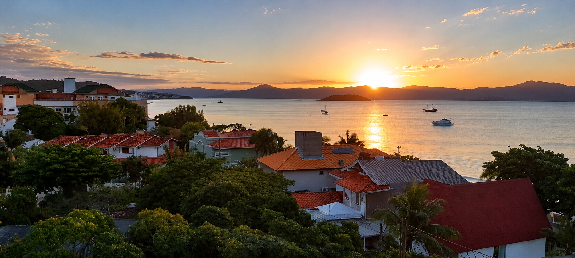 Atardecer sobre la Bahía Norte con casas, vegetación y embarcaciones
