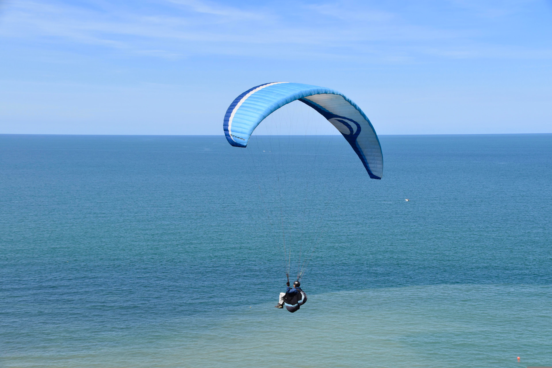 Parapente sobrevolando el mar azul en un día despejado