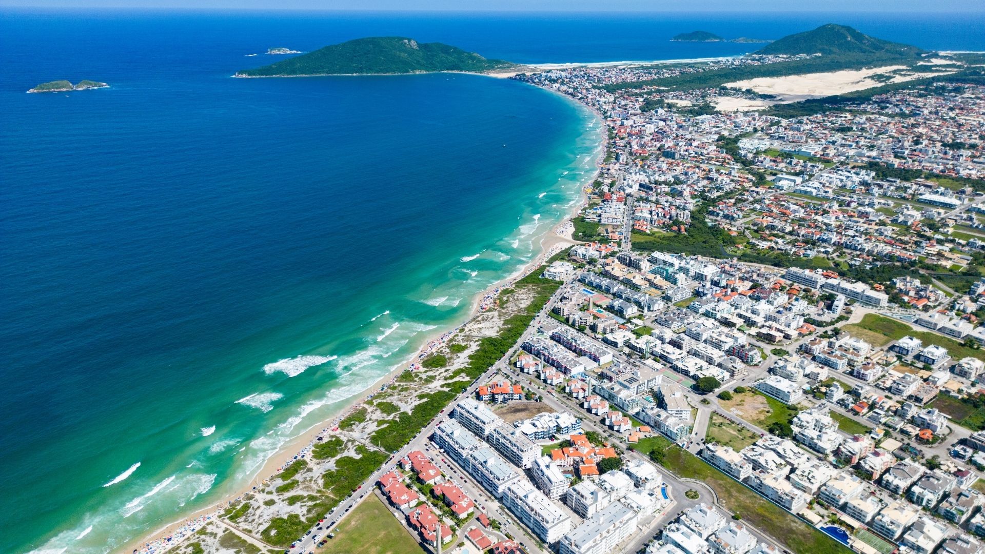 Vista aérea de la playa de Ingleses con mar turquesa, dunas y barrio residencial extenso