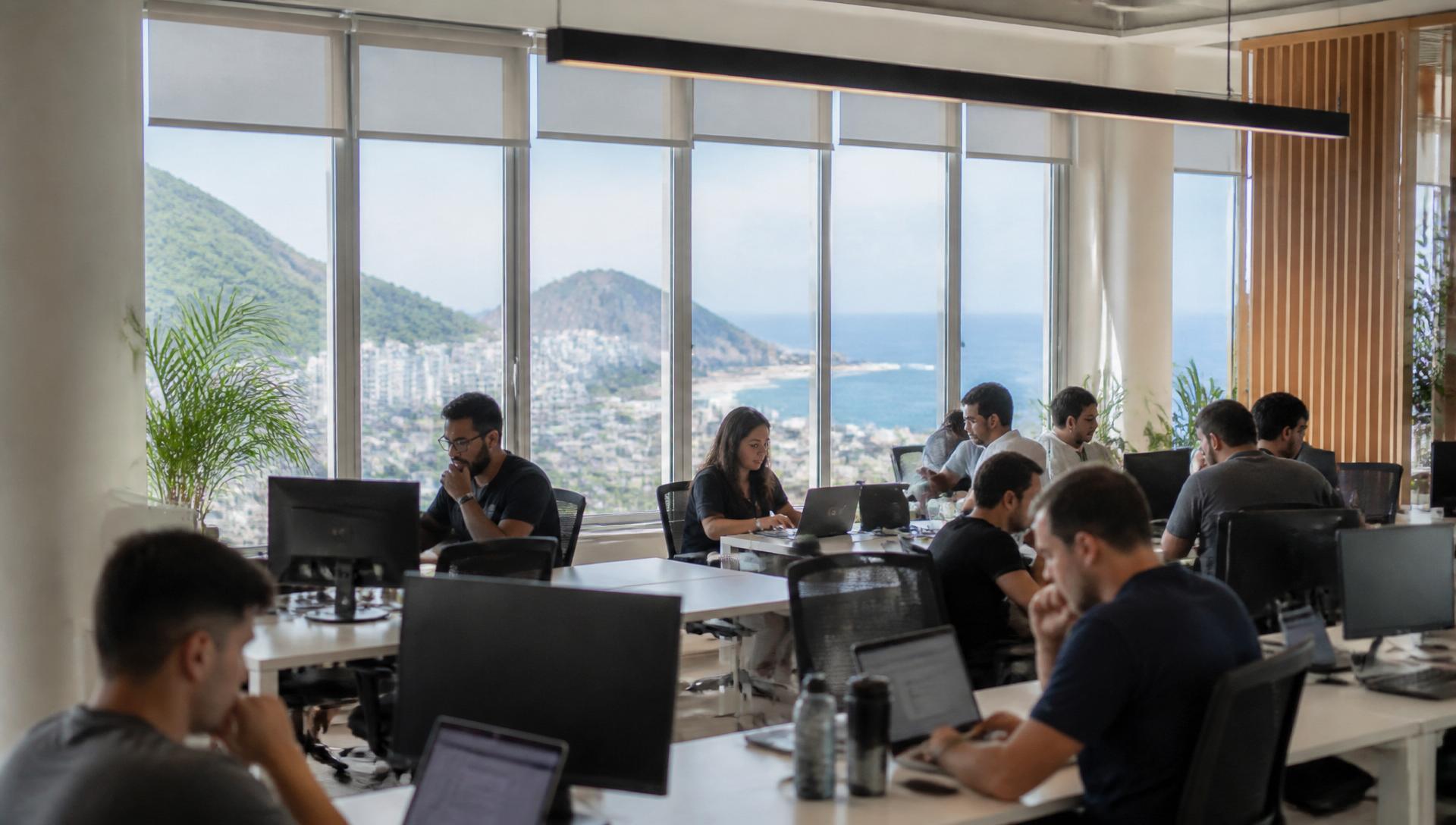 Oficina luminosa de tecnología con ventanales y vista al mar